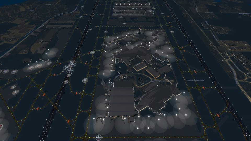 Heathrow nachts von oben: zwei beleuchtete Pisten, gelbgrüne Lichter der Rollwege, angestrahlte Abstellpositionen rund um die Terminals