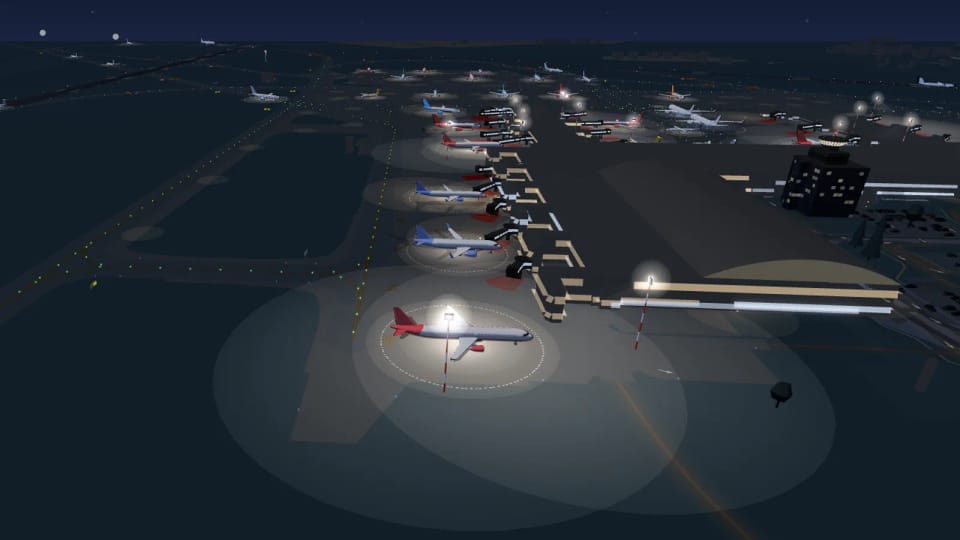 Die Prager Abstellpositionen bei Nacht: Flugzeuge an den Fluggastbrücken, Lichtpfützen unter den Masten, die Verglasung des Terminals und im Hintergrund der Kontrollturm