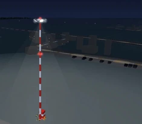 Ein gestreifter Vorfeldmast in Prag bei Nacht mit beleuchteter Krone, roten Hindernisfeuern und einem Sockel am Fuß, dahinter das Vorfeld und das Terminal
