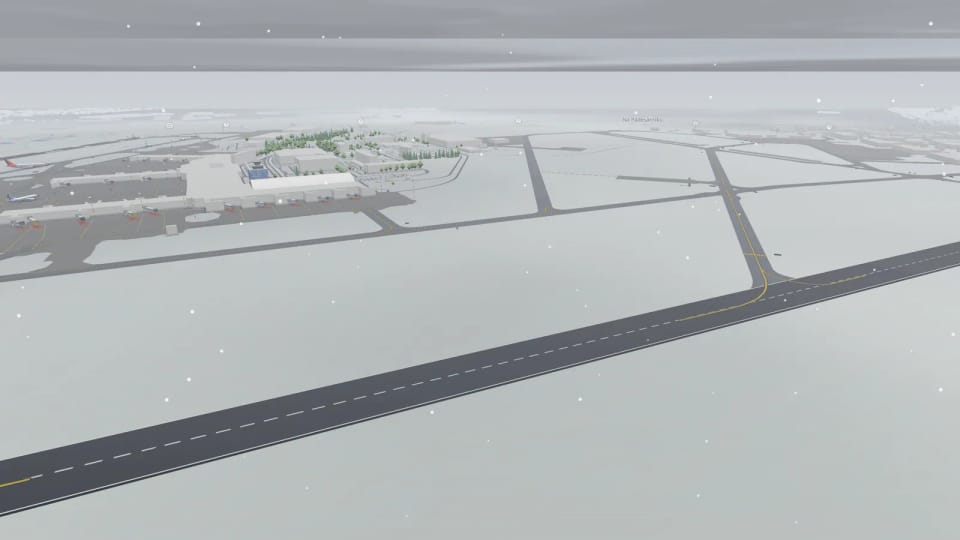 Neve in aeroporto: erba e campagna bianche intorno alla pista e alle vie di rullaggio scure, fiocchi che cadono